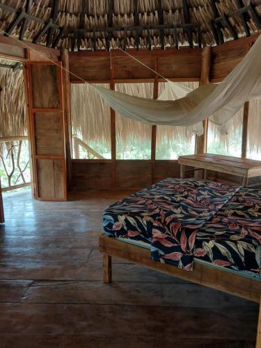 a bedroom with a bed with a hammock in it at Hostel Nugeku in Rincón