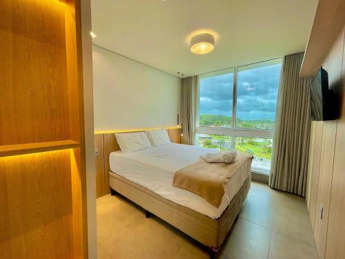 - une chambre avec un lit et une grande fenêtre dans l'établissement Livin' Resort Home - 505/2, à Xangri-lá