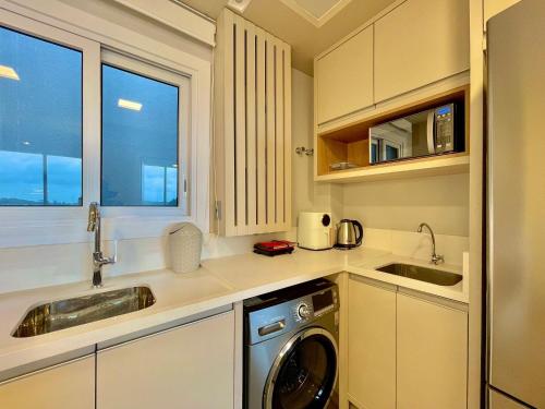 Il comprend une cuisine équipée d'un évier et d'un lave-linge. dans l'établissement Livin' Resort Home - 505/2, à Xangri-lá