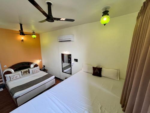 a bedroom with two beds and a ceiling fan at Hotel The Tiger in Udaipur