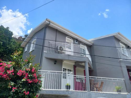 a gray house with white balconies and pink flowers at VILLAS AUMIS 2MR in Fort-de-France