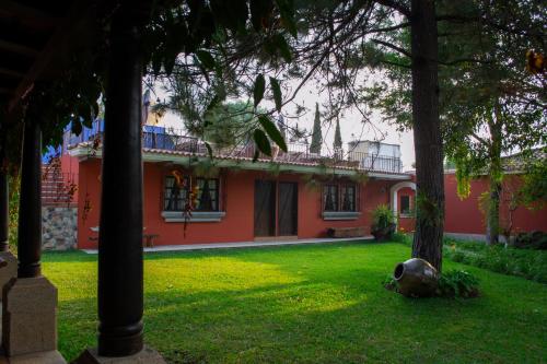 a red house with trees in front of it at Santa Margarita in Antigua Guatemala