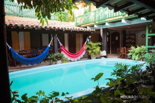 a swimming pool with hammocks in front of a building at Villas Boas in Arraial do Cabo