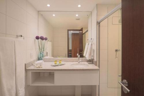 a bathroom with a sink and a large mirror at Betel Beach Flat Boa Viagem in Recife