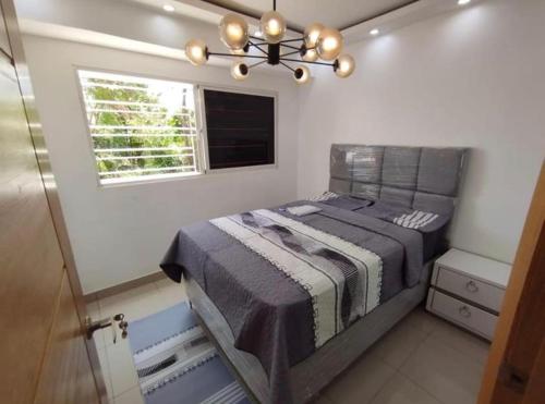 a bedroom with a bed with a window and a chandelier at APT Estevez in Pantoja