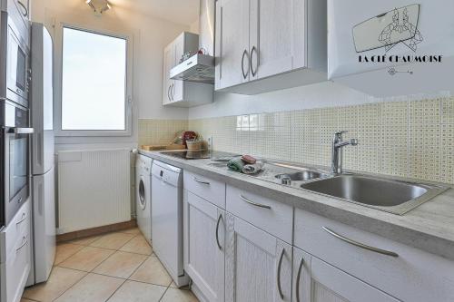 une cuisine avec des armoires blanches, un évier et une fenêtre dans l'établissement Antares - Appartement vue mer - Les sables, à Les Sables-dʼOlonne