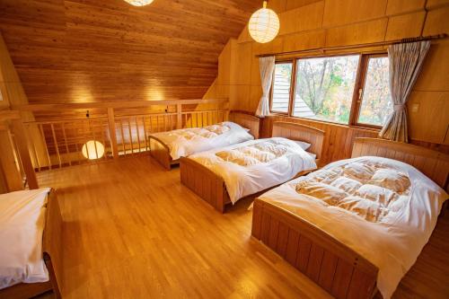 Morinoyu Hotel Hanakagura في اساهيكاو: غرفة نوم بسريرين في غرفة خشبية