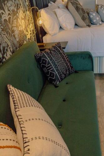a green couch with pillows in a hotel room at Luxury Menlyn Maine Apartment in Pretoria