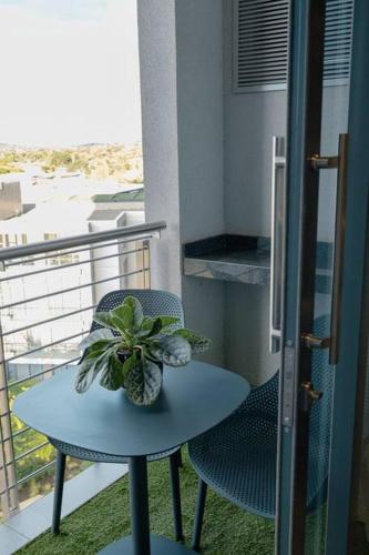 a table and chair on a balcony with a plant at Luxury Menlyn Maine Apartment in Pretoria