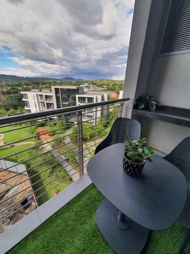 a table on a balcony with a plant on it at Luxury Menlyn Maine Apartment in Pretoria