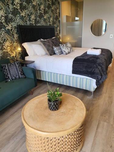 a bedroom with a bed and a table and a couch at Luxury Menlyn Maine Apartment in Pretoria
