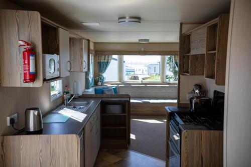 Una cocina con una gran ventana y una sala de estar. en Littlesea Caravan, en Weymouth