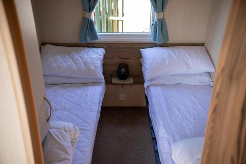 two beds in a small room with a window at Littlesea Caravan in Weymouth