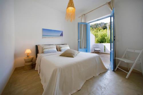 a white bedroom with a bed and a large window at Villetta Acacie in San Vito lo Capo