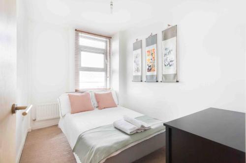 a white room with a bed with a window at Spacious 2 Bedroom Apartment In Central Near tube in London