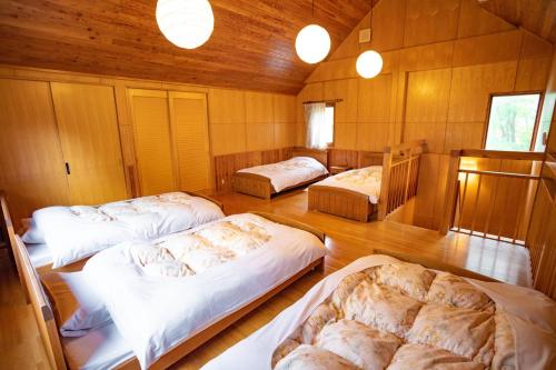 three beds in a room with wooden walls at Morinoyu Hotel Hanakagura in Asahikawa