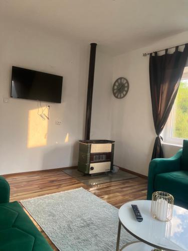 a living room with a couch and a table and a clock at Obrov in Bijelo Polje
