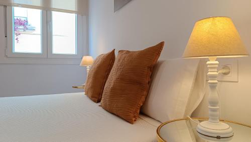 łóżko z poduszkami i stół z lampką w obiekcie Sherryflat Torneria- Parking w mieście Jerez de la Frontera
