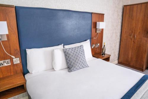 a bedroom with a large bed with a blue headboard at The Western Hotel in Galway