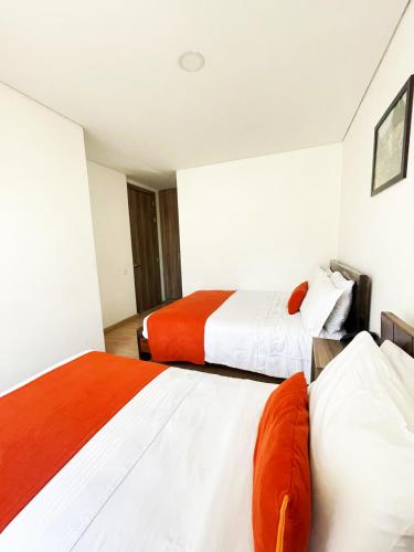 two beds in a room with orange and white at Hotel Portal de los Andes in Bogotá