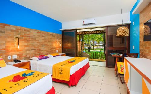 a hotel room with two beds and a balcony at Hotel Village Porto De Galinhas in Porto De Galinhas