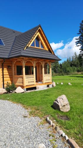 a log cabin with a porch and a rock at Góralska Chata przy Dolinie Chochołowskiej - gorąca balia in Witów