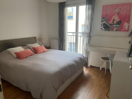 Schlafzimmer mit einem Bett, einem Schreibtisch und einem Fenster in der Unterkunft Chaleureux et lumineux appartement in Puteaux
