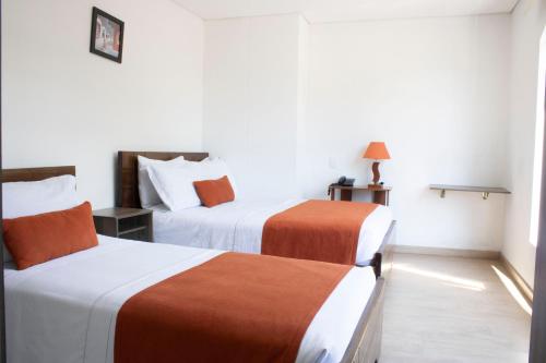 a hotel room with two beds with orange and white sheets at Hotel Portal de los Andes in Bogotá