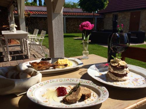 a table with three plates of food and a glass of wine at Penzion V polích in Malé Číčovice
