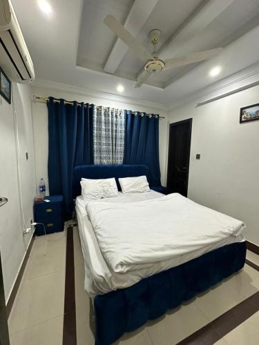 uma cama grande num quarto com cortinas azuis em Areej tower E-11/3 Islamabad em Islamabad