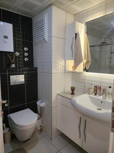 a white bathroom with a toilet and a sink at Cozy fancy Sea view next to the Beach and the Mall, in the mid of Alanya Mahmutlar! in Alanya