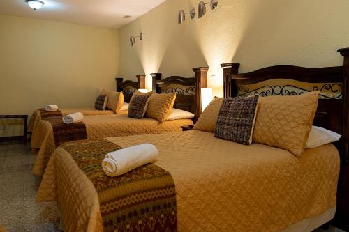 a hotel room with three beds in a room at Hostal Donde Regina in Guatemala