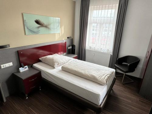a bedroom with a bed and a chair and a window at Ariston Hotel in Sindelfingen