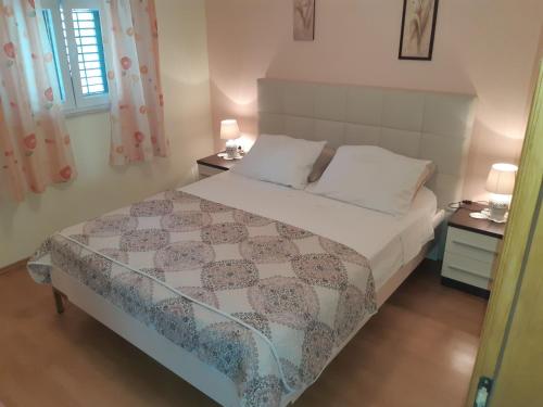 a bedroom with a bed and two night stands with lamps at Apartman Luna in Smokvica