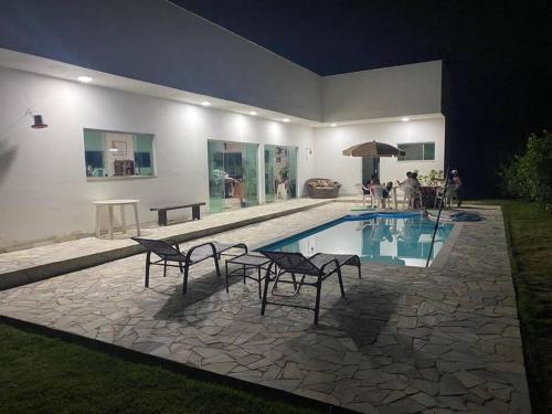 Casa con piscina con sillas y sombrilla en Sítio agradável com piscina em Condomínio fechado en Brumadinho