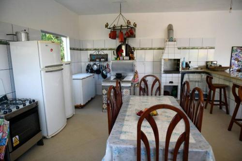 a kitchen with a table and a white refrigerator at Sítio agradável com piscina em Condomínio fechado in Brumadinho