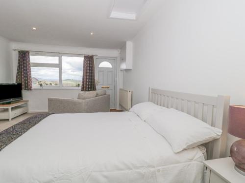 um quarto branco com uma cama e uma cadeira em 27 Fernhill Heights em Bridport