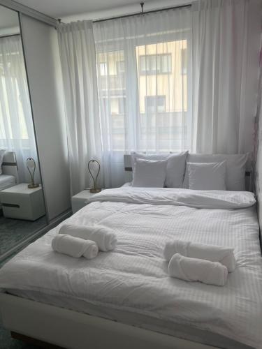 a white bed with two towels on top of it at Tropical Jungle Apartament in Otwock