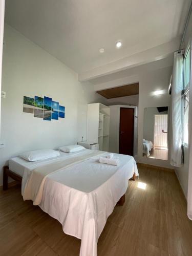 um quarto com uma grande cama branca e 2 almofadas em Hospedaje MorroSP em Morro de São Paulo