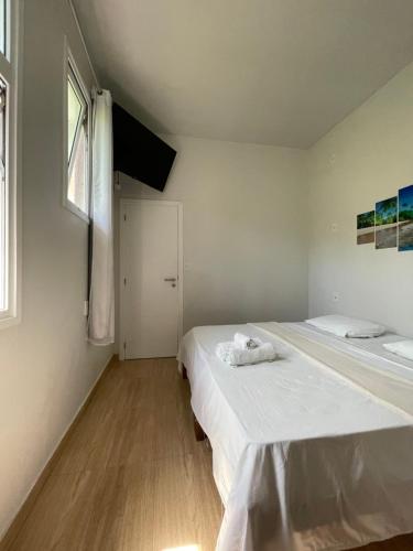 two beds in a white room with a window at Hospedaje MorroSP in Morro de São Paulo