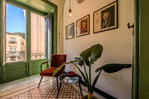 une chambre avec une plante, une chaise et une fenêtre dans l'établissement Palazzo Villelmi, à Cefalù