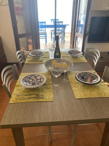 a wooden table with plates and wine glasses on it at Casa Emma in Favignana