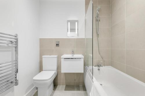 a white bathroom with a toilet and a bath tub at Spacious Studio Apartment in Central Newbury in Newbury