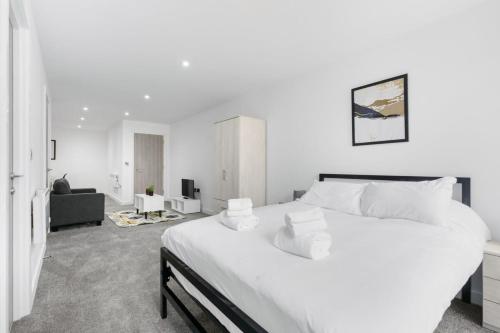 a white bedroom with a large bed and a living room at Spacious Studio Apartment in Central Newbury in Newbury