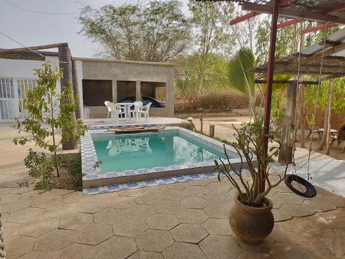 uma pequena piscina com uma mesa e cadeiras num quintal em La Maison Blanche em Ndangane