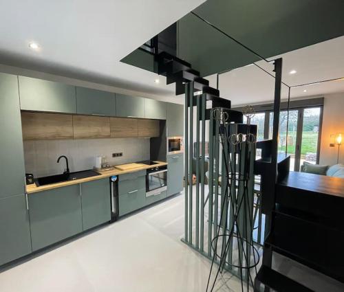 a kitchen with green cabinets and a staircase in a house at Logement N2 tout confort - proche de Giverny in Limetz