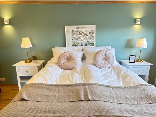 a large bed with two pillows on it with two lamps at Selið Farm Stay - Guesthouse in Álftanes