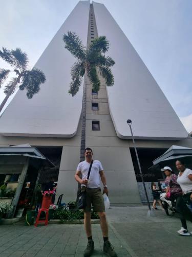 麥德林的住宿－Hotel Medellin op，站在棕榈树建筑前面的人