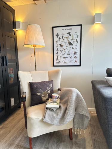 a living room with a chair with a blanket on it at Selið Farm Stay - Guesthouse in Álftanes