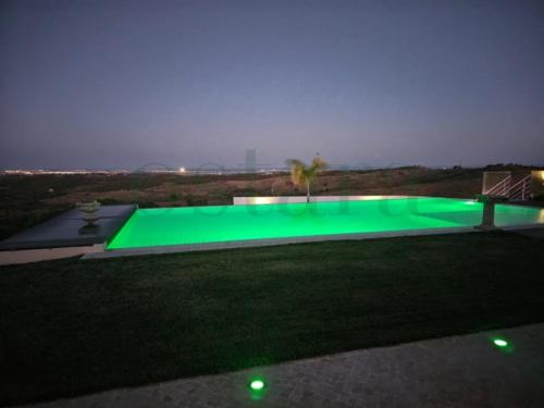 una piscina verde en medio de un patio por la noche en Glycine Jasmim, en Castro Marim